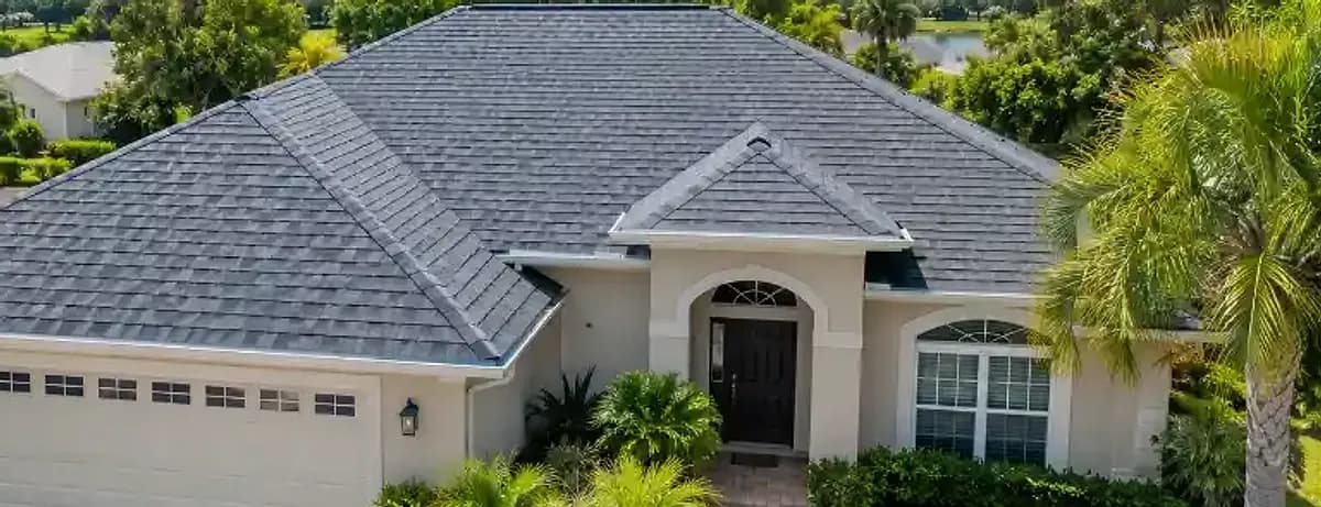 The same stucco home with a new charcoal architectural shingle roof after roof replacement